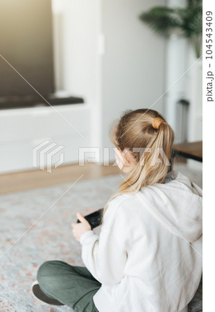 Girl playing video game at home 104543409