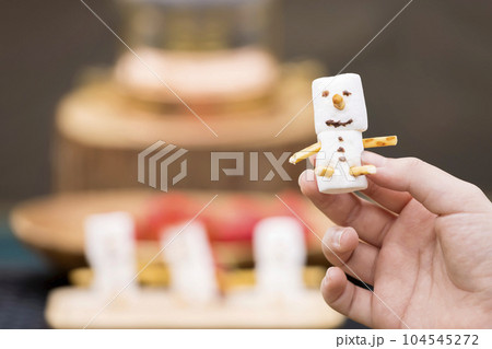 キャンプ、アウトドアイメージ　ましゅまろで作った雪だるまを持つ子供の手 104545272