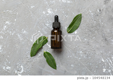 Natural Mint Essential Oil in a Glass Bottle. organic cosmetics with herbal extracts of mint on colored background 104548134
