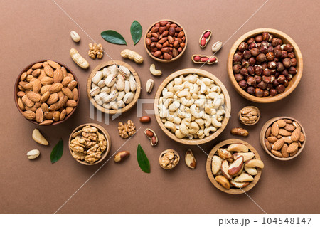 mixed nuts in wooden bowl. Mix of various nuts on colored background. pistachios, cashews, walnuts, hazelnuts, peanuts and brazil nuts 104548147