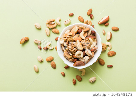 mixed nuts in bowl. Mix of various nuts on colored background. pistachios, cashews, walnuts, hazelnuts, peanuts and brazil nuts 104548172