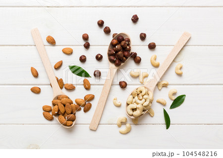Assortment of nuts in wooden spoon on colored table. Cashew, hazelnuts, walnuts, almonds. Mix of nuts Top view with copy space 104548216