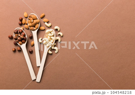 Assortment of nuts in wooden spoon on colored table. Cashew, hazelnuts, walnuts, almonds. Mix of nuts Top view with copy space Assortment of nuts in wooden spoon on colored table. Cashew, hazelnuts, walnuts, almonds. Mix of nuts Top view with copy space 104548218