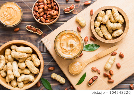 Bowl of peanut butter and peanuts on table background. top view with copy space. Creamy peanut pasta in small bowl Bowl of peanut butter and peanuts on table background. top view with copy space. Creamy peanut pasta in small bowl 104548226