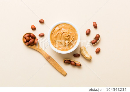 Bowl of peanut butter and peanuts on table background. top view with copy space. Creamy peanut pasta in small bowl Bowl of peanut butter and peanuts on table background. top view with copy space. Creamy peanut pasta in small bowl 104548235