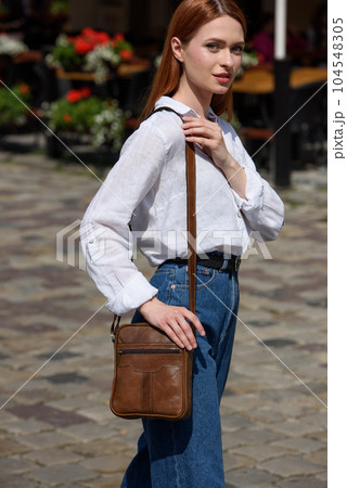 photo of a woman with a small brown leather bag. 104548305