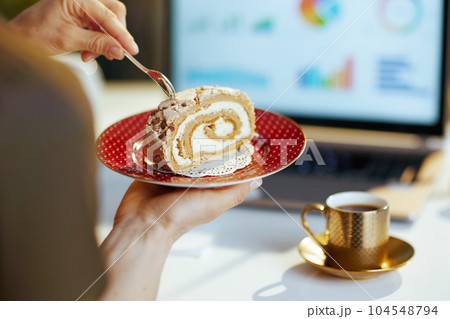 Closeup on modern woman with laptop and piece of cake Closeup on modern woman with laptop and piece of cake 104548794