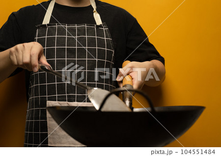 Chief wearing apron holding spatula and frying pan isolated on yellow background 104551484