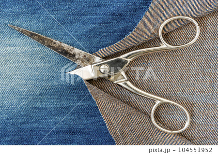 Metal scissors and ripped denim jeans Metal scissors and ripped denim jeans 104551952