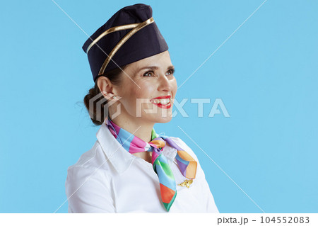 smiling modern female air hostess on blue looking into distance 104552083