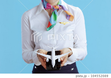 Female stewardess on blue showing little airplane and smartphone 104552089