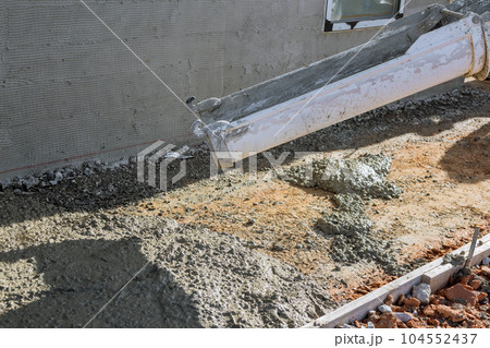 Concrete mixing truck pours concrete onto building site surrounding newly constructed home so that it can make pavement Concrete mixing truck pours concrete onto building site surrounding newly constructed home so that it can make pavement 104552437
