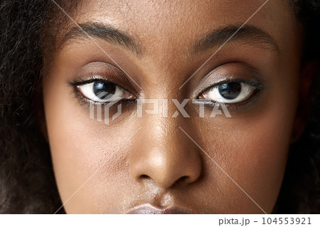 Close-up image of young african woman, eyes, nose. Model looking at camera. Beauty standards and acceptance 104553921