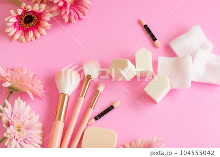 ピンク色の背景に並べたメイクブラシとパフとスポンジなどのメイクツール 104555042