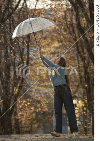 Beautiful young woman fun with transparent umbrella. Happy young woman with long hair in autumn park. Beautiful young woman fun with transparent umbrella. Happy young woman with long hair in autumn park. 104555103