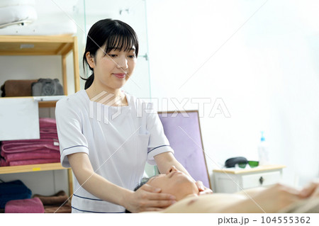 男性に施術をする若いエスティシャンの女性 男性に施術をする若いエスティシャンの女性 104555362