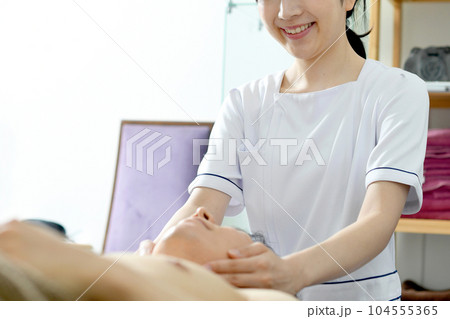 男性に施術をする若いエスティシャンの女性 男性に施術をする若いエスティシャンの女性 104555365