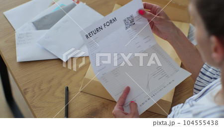 Close up female hands putting letter in envelop return form. Woman sends a return form by letter. Close up female hands putting letter in envelop return form. Woman sends a return form by letter. 104555438