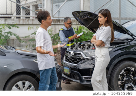 An unset young woman talking angryly to a man who accidentally drove his car and hit her car while insurance agent checking the damage of the accident An unset young woman talking angryly to a man who accidentally drove his car and hit her car while insurance agent checking the damage of the accident 104555969