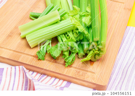 Fresh Celery Stem and Chopped Celery Sticks on Wooden Cutting Board 104556151