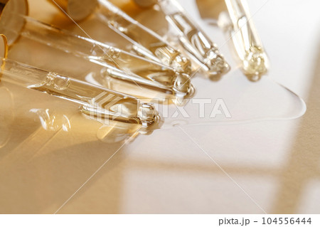 Pipettes with oil or serum on a golden background. 104556444