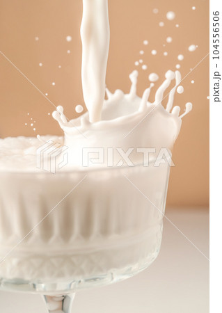 Milk pours into a beautiful crystal glass and splashes around. 104556506