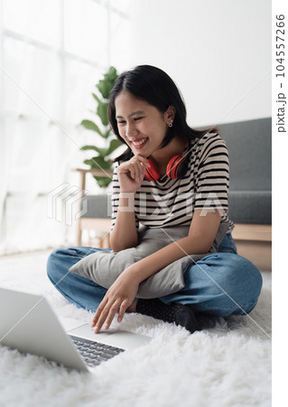 Young asian relaxed smiling pretty woman relaxing with laptop at home. Female feeling joy enjoying with mobile phone on cozy couch 104557266