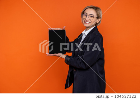 Smiling joyful woman wearing black official style suit showing empty screen of tablet 104557322