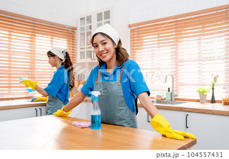 Portrait Asian housekeeper or housemaid stand with touch top of table in kitchen smile to camera Portrait Asian housekeeper or housemaid stand with touch top of table in kitchen smile to camera 104557431