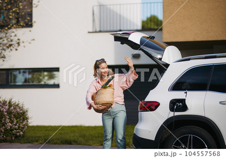 Woman coming back from grocery store, waiting for car charging. Woman coming back from grocery store, waiting for car charging. 104557568