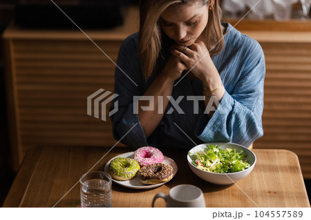 Young woman having diet, deciding between salad and donuts. Young woman having diet, deciding between salad and donuts. 104557589