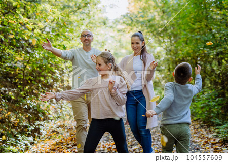 Happy family having fun with a foliage in autumn forest. 104557609