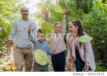 Happy family having fun with a foliage in autumn forest. 104557610