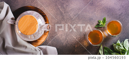 Calming green mint tea in cups and teapot on the table top view web banner Calming green mint tea in cups and teapot on the table top view web banner 104560193