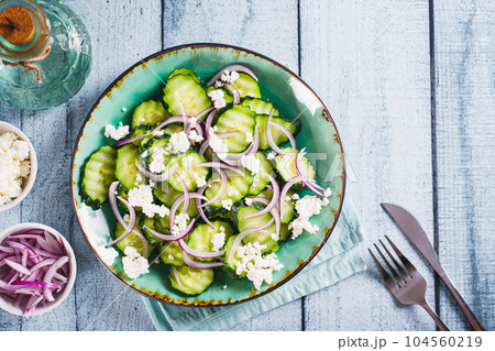Fresh cucumber, ricotta and red onion salad on a plate on the table top view 104560219
