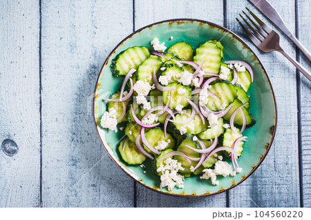 Close up of fresh cucumber, ricotta and red onion salad on a plate on the table top view Close up of fresh cucumber, ricotta and red onion salad on a plate on the table top view 104560220