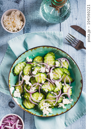 Diet salad of cucumbers, red onions and ricotta on a plate on the table top and vertical view Diet salad of cucumbers, red onions and ricotta on a plate on the table top and vertical view 104560221