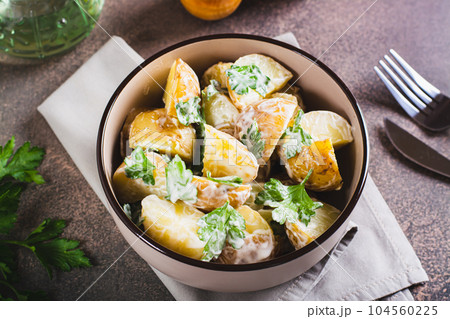 Delicious potato salad with parsley and mayonnaise in a plate on the table 104560225