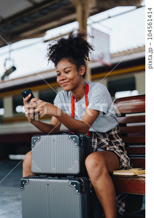 Asian teenage girl african american traveling using smartphone moblie while waiting for a train at a station 104561414