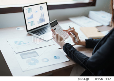 businesswoman or accountant working on calculator and laptop computer to calculate business data during using accountancy document at office. 104561442