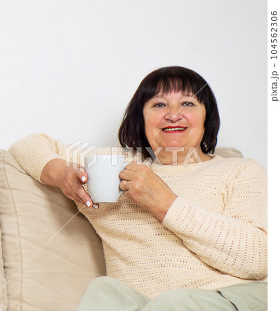 Happy relaxed old woman in good mood drinking a cup of coffee or hot tea at home. Happy relaxed old woman in good mood drinking a cup of coffee or hot tea at home. 104562306