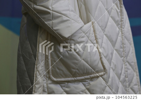 Close-up fragment of a white waterproof raincoat with a sleeve and a pocket. Close-up fragment of a white waterproof raincoat with a sleeve and a pocket. 104563225