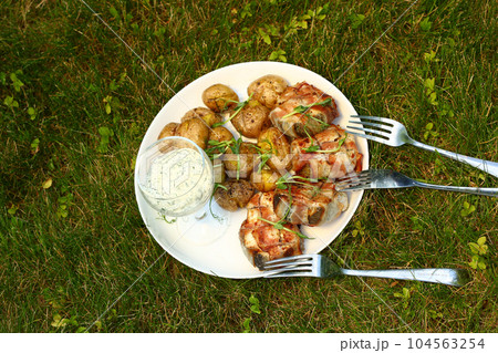 heck fish steaks roasted in bacon ham roll with new jacket potatoes and green arugula closeup photo 104563254