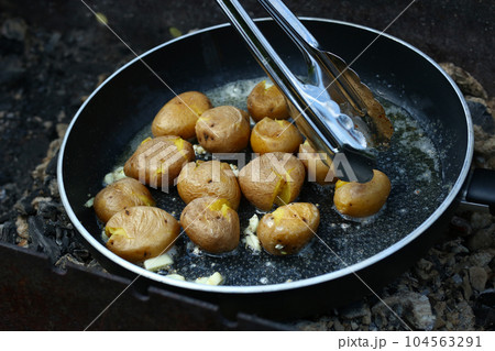 new jacket potatoes roasting in frying pan on grill coals closeup photo new jacket potatoes roasting in frying pan on grill coals closeup photo 104563291