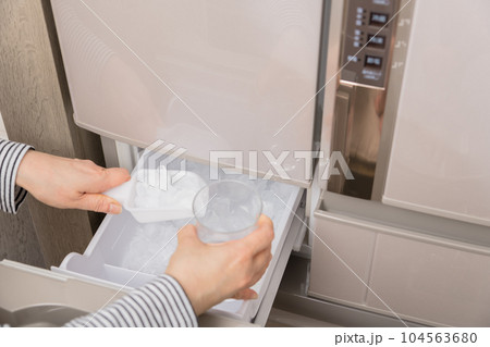 【製氷室から氷をグラスに入れる主婦】 104563680
