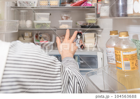 【冷蔵室からタッパを取り出す主婦】 104563688