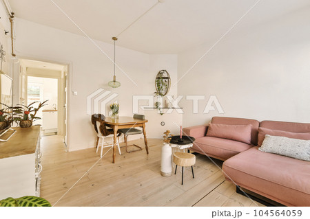 a living room with a pink couch and some plants on the table in front of the couch is an open door 104564059