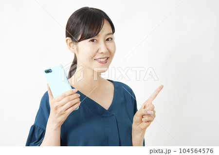 スマートフォンを持って右側を指差すミドルエイジ女性　白背景 104564576