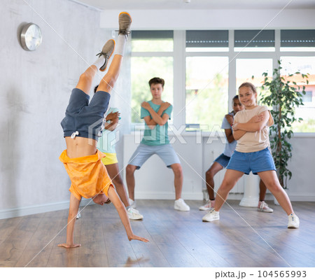 Boy performs handstand during break dance workout with peers friends 104565993