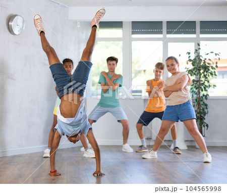 African boy performs handstand during break dance workout with peers friends 104565998